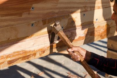 Low angle view of man working on wooden plank