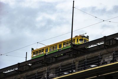 Low angle view of railroad track with a streetcar against sky