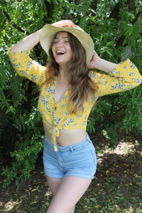 Cheerful woman standing against plant