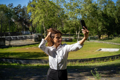 Rear view of woman with arms raised standing on field