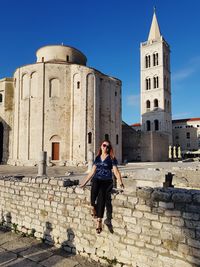 Full length of young woman against building