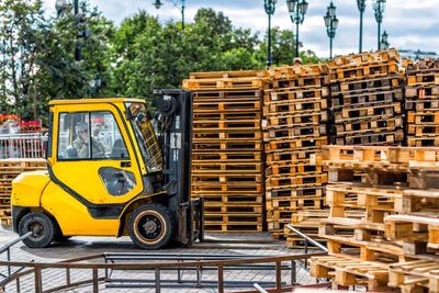 Forklift by wooden objects against trees