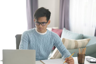 Young man using mobile phone while sitting on table