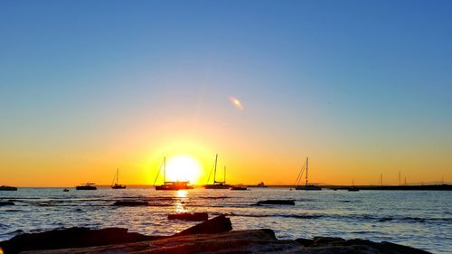 Silhouette boats on sea against sky during sunset