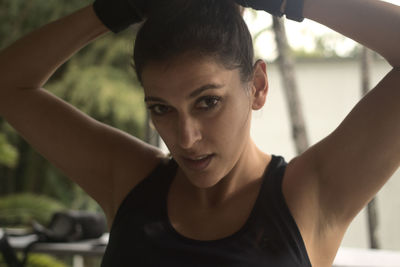 Medium shot of a hispanic woman in a shirt and fingerless gloves fixing her hair