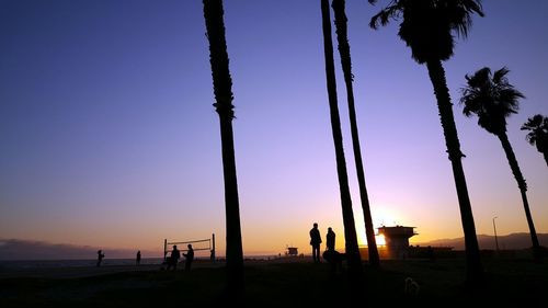 Silhouette people on beach against sky during sunset