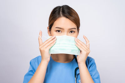 Portrait of woman covering face against white background