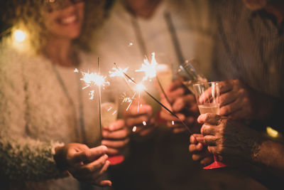 Midsection of people holding sparkler at night