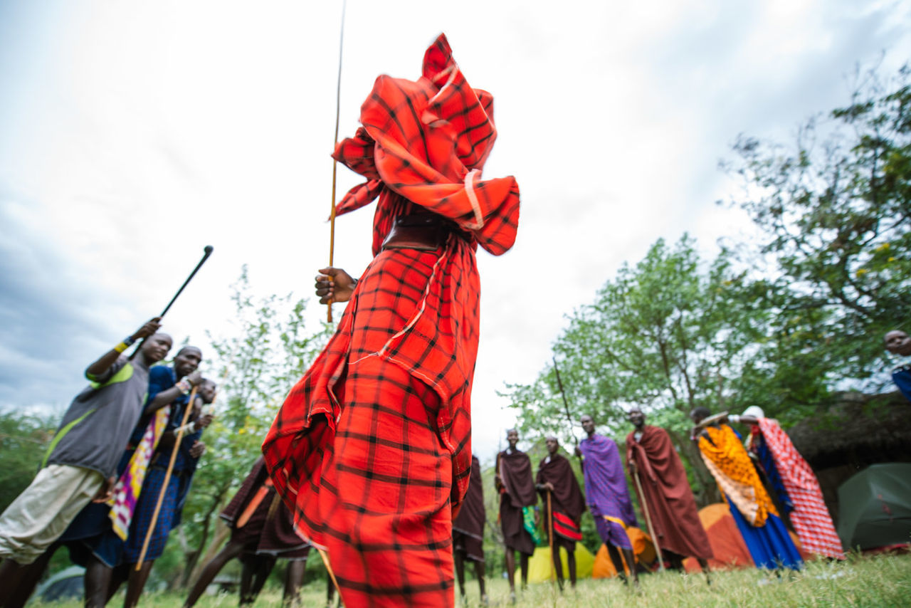 sky, red, nature, day, focus on foreground, real people, clothing, multi colored, low angle view, cloud - sky, plant, people, outdoors, tree, holding, flag, three quarter length, traditional clothing, festival