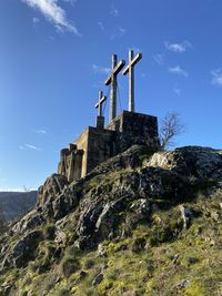 Low angle view of cross on mountain against sky