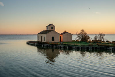 House by sea against sky during sunset