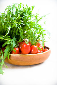 Close-up of fresh herbs and tomatoes in bowl on white background