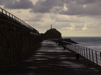 Footpath by sea against sky