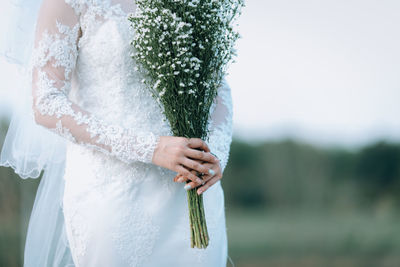 Midsection of woman holding umbrella standing against plants