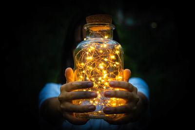 Midsection of teenage girl holding jar with illuminated lights