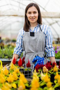 Portrait of young woman standing amidst plants