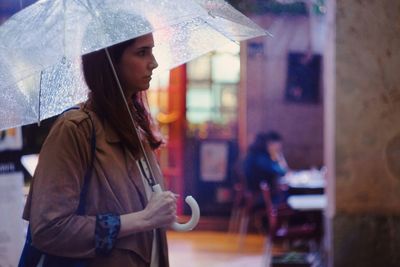 Side view of woman with umbrella walking on street during monsoon