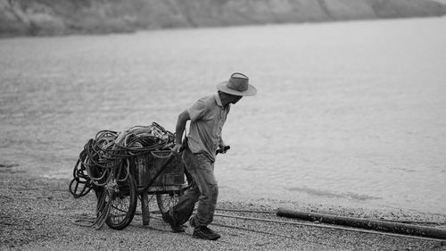 Man pulling cart with ropes at beach