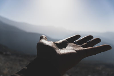 Close-up of hand against sky