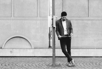 Full length of young woman standing on mobile phone