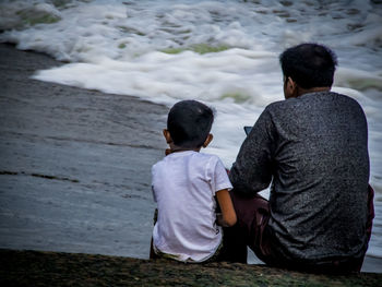 Rear view of friends sitting at shore