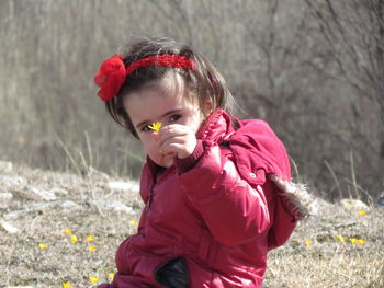 Portrait of girl holding tiny flower on field