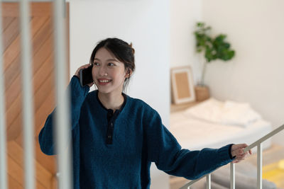 Portrait of young woman standing against wall
