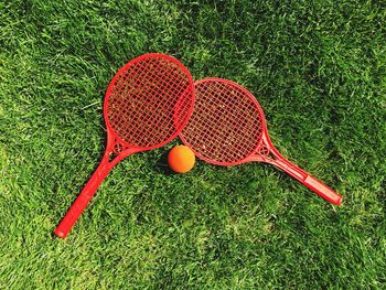 Directly above shot of red tennis rackets by ball on court