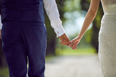 Midsection of couple holding hands after married