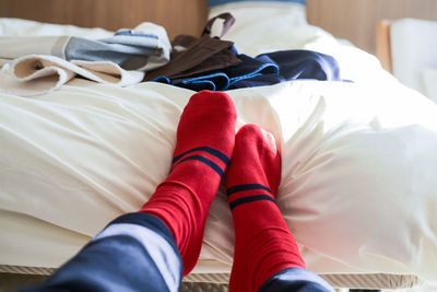 Low section of person wearing red socks on bed