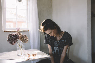 Woman sitting on table by window at home