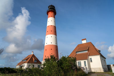 Low angle view of lighthouse amidst buildings against sky