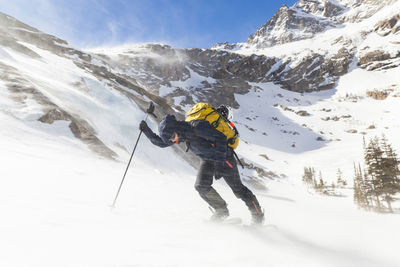 Hiker battles wind above black lake, rocky mountain national park