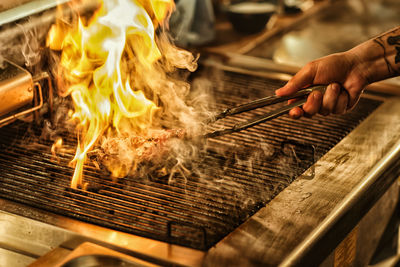 Cropped hand preparing food on barbecue grill