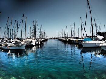 Sailboats moored in sea against clear sky