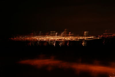 Reflection of illuminated city in calm sea at night