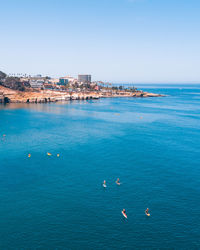 High angle view of buildings by sea against clear sky