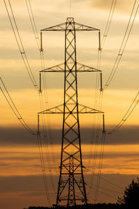 Low angle view of silhouette electricity pylon against sky during sunset