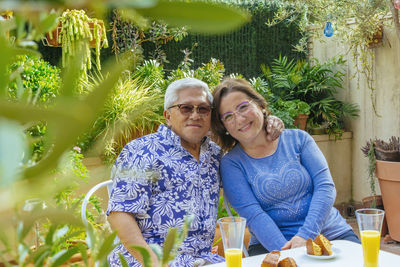 Portrait of smiling senior couple having breakfast while sitting in yard