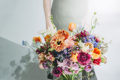 Midsection of female florist by colorful flowers
