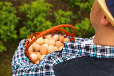 Man holding many eggs in basket. men holding whole basket of brown organic eggs on nature green 