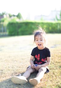 Portrait of cute girl sitting on field
