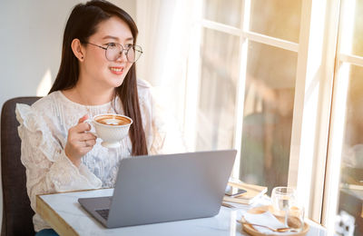 Young woman using smart phone in laptop