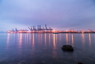 Illuminated pier over sea against sky