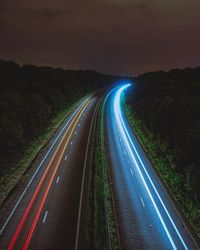 Light trails on road against sky at night