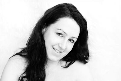 Close-up portrait of smiling young woman over white background