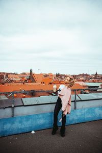 Rear view of man looking at cityscape against sky