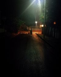 Man walking on illuminated street at night