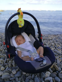 Boy sitting on pebbles at beach