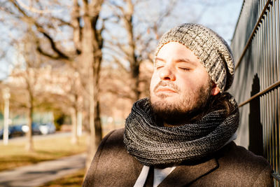 Close-up of man with eyes closed wearing scarf standing outdoors